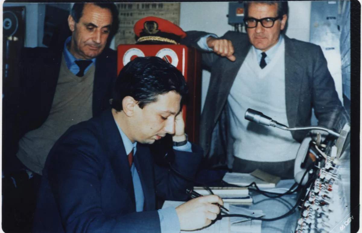 Tre ferrovieri al lavoro davanti a un banco di controllo ferroviario
